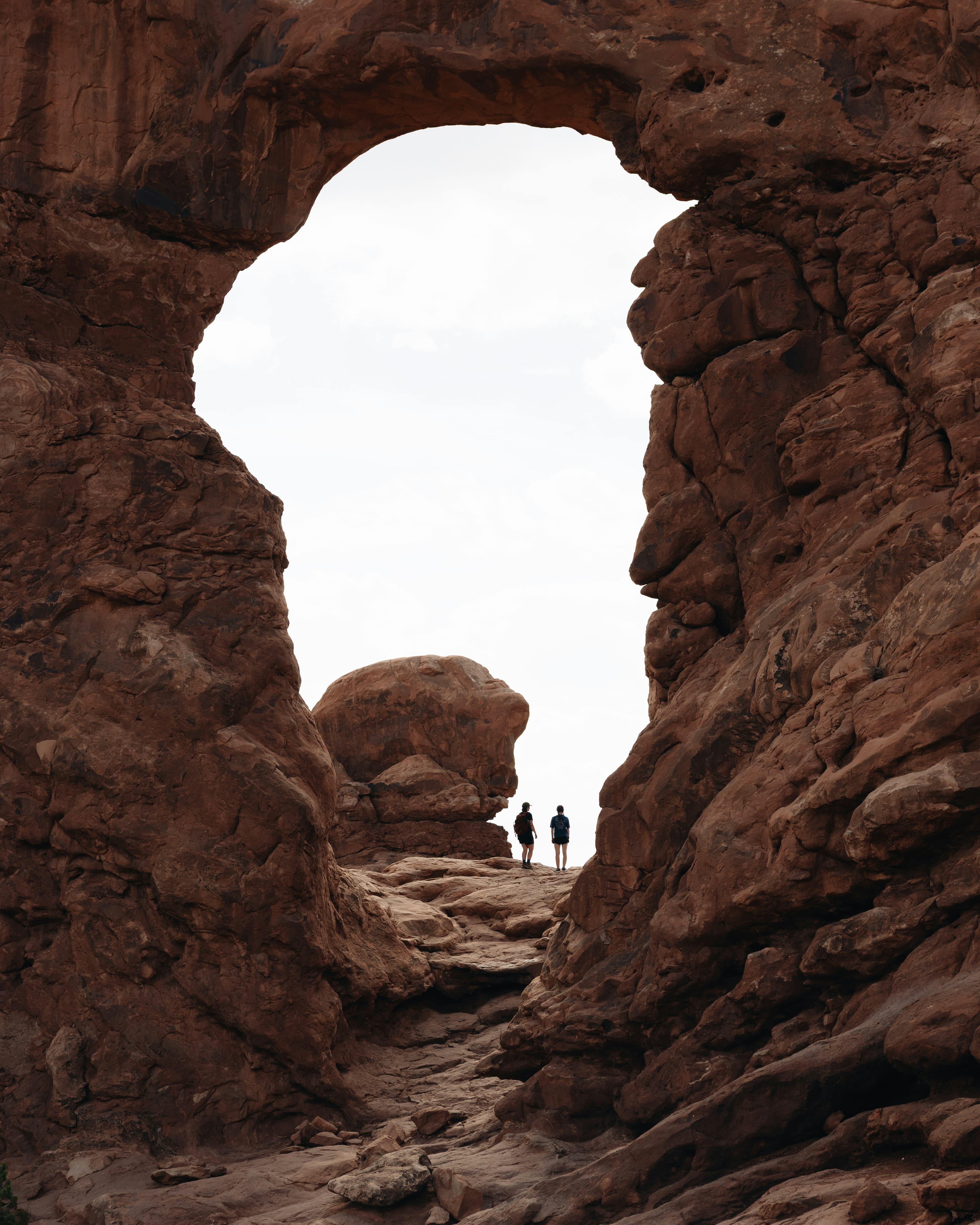 Dos personas caminan bajo un arco de piedra